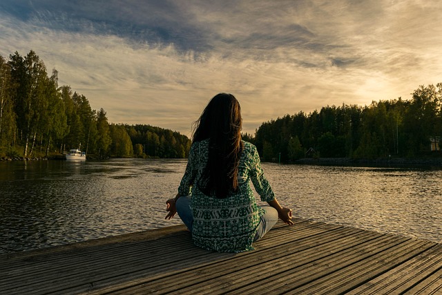 Person sitting peacefully in nature practicing mindfulness and grounding exercises